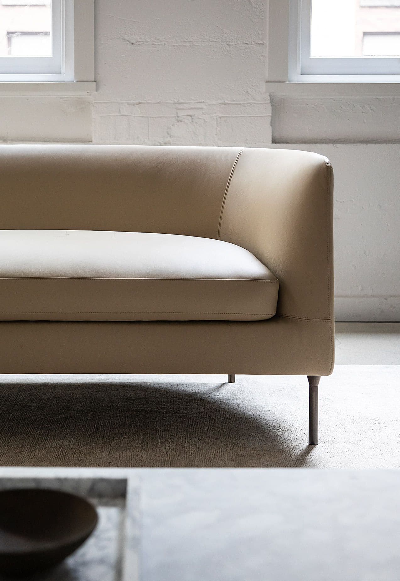 Bensen Delta Club Chair 2 Seater in beige leather: close view of the arm, seat cushion and a dark metal leg